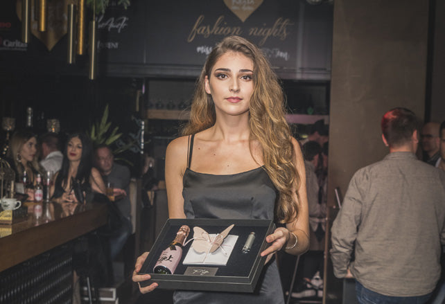 A participant holding an open gift box at a charitable fashion event.