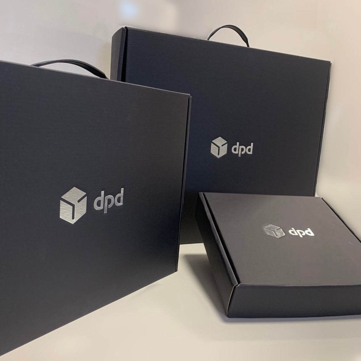A collection of black DPD gift boxes and handled packaging with silver logos.